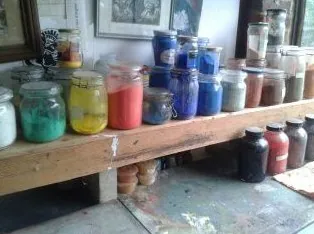 Jars of pigment on a wooden shelf