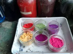 A tray of powdered pigments in red, green, violet, ocher and pink