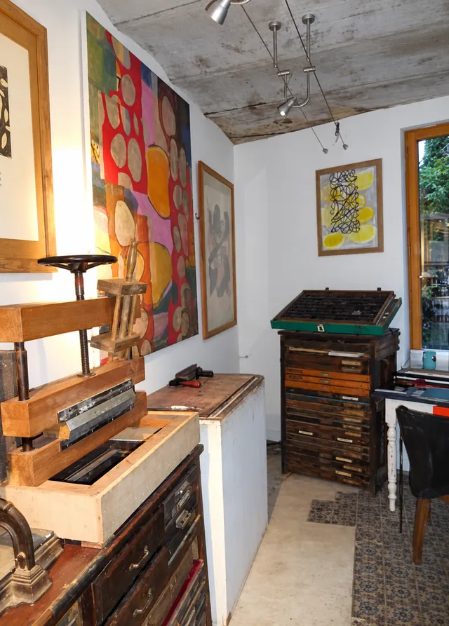 The print room of the Atelier Reine Brunehaut, with a press, type cases and framed prints